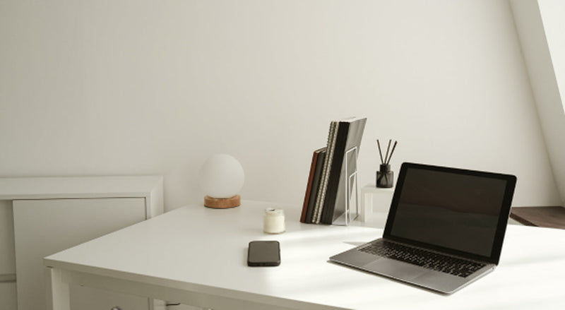 Laptop and notebook on a white desk representing free marketing strategies for small brands
